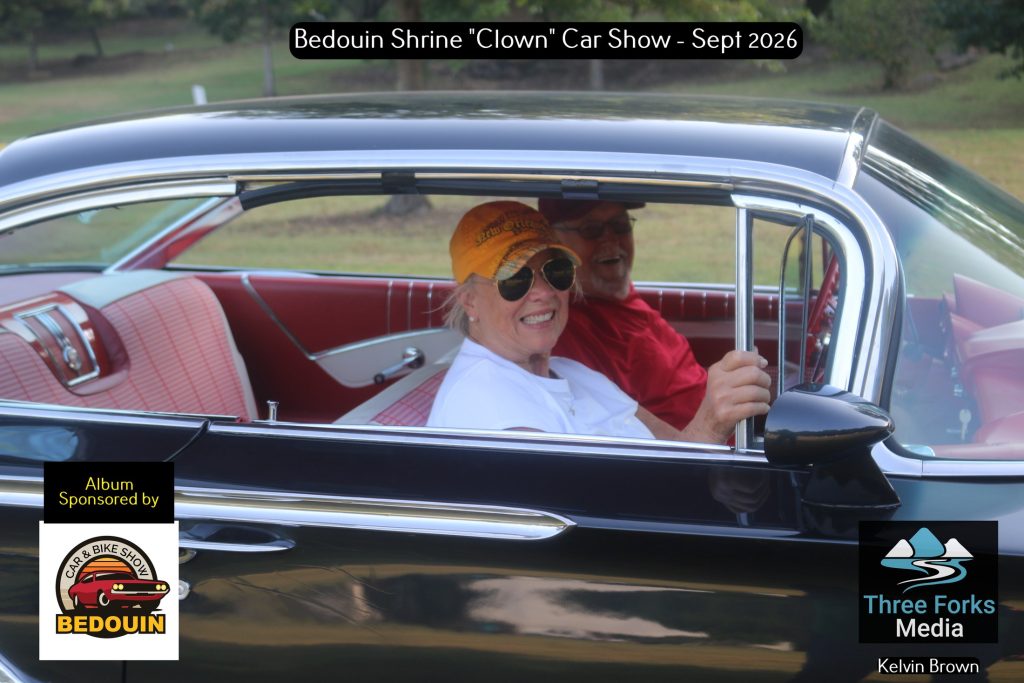 Couple smiling inside a classic black car with red interior at the Bedouin Shrine Car Show