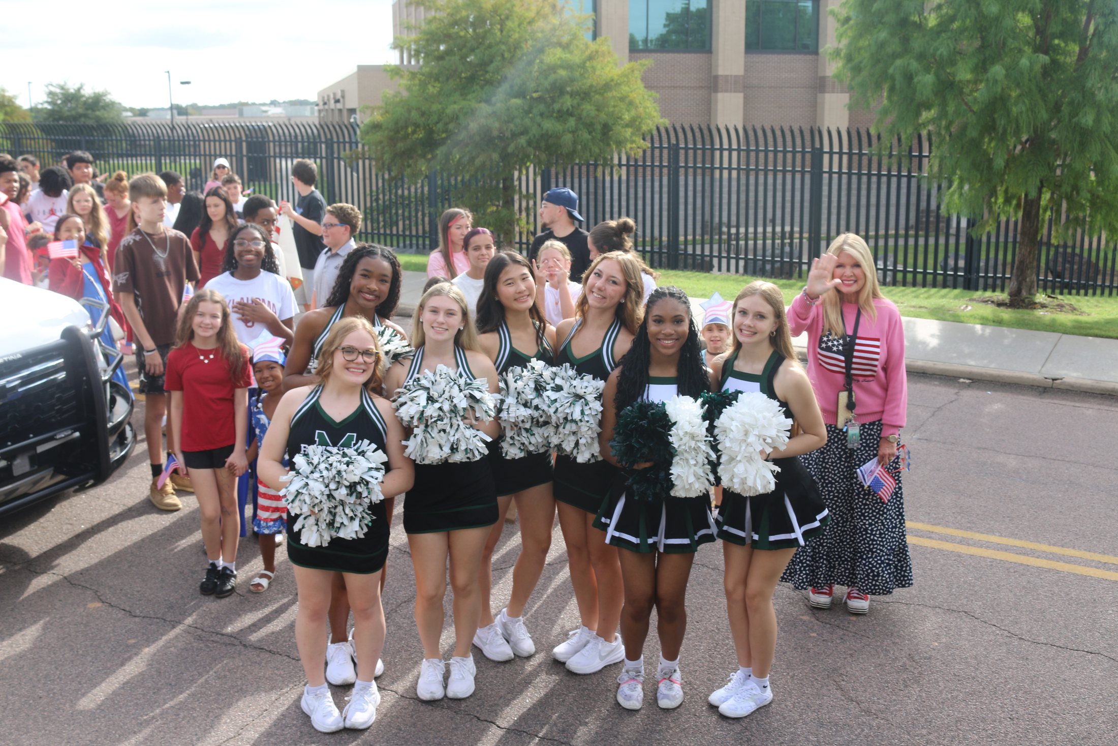 MHS cheerleaders in green and black uniforms with pom poms at the Patriotic Parade