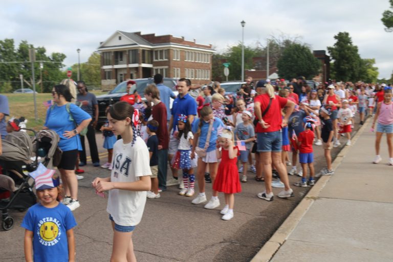 Patriotic Parade crowd marching down downtown Muskogee street with red white and blue colors