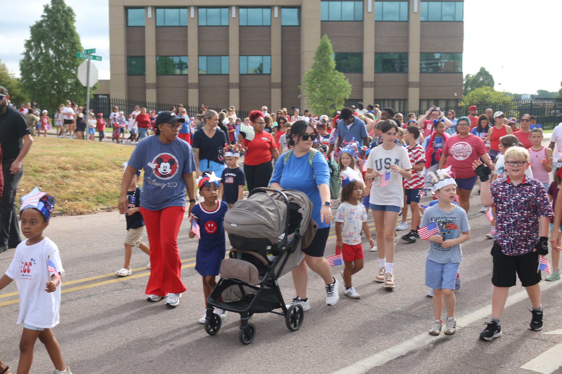 Families with strollers and young children carrying American flags at the Patriotic Parade